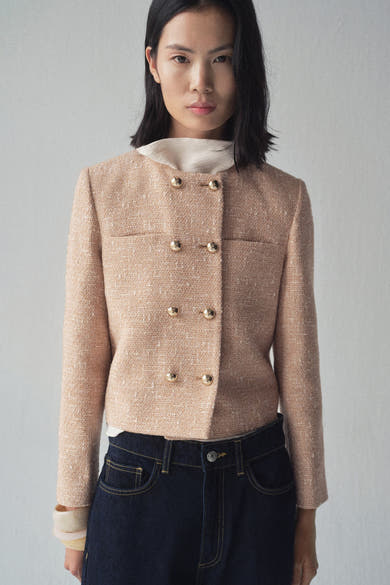 Beige blazer van MANGO met gouden knopen, gedragen over een licht topje en een indigoblauwe jeans.