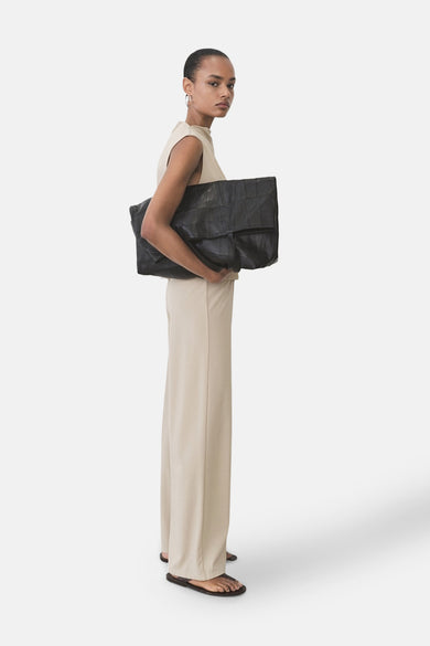 Pantalon beige de MANGO, long et ample, porté avec un haut neutre et des sandales.