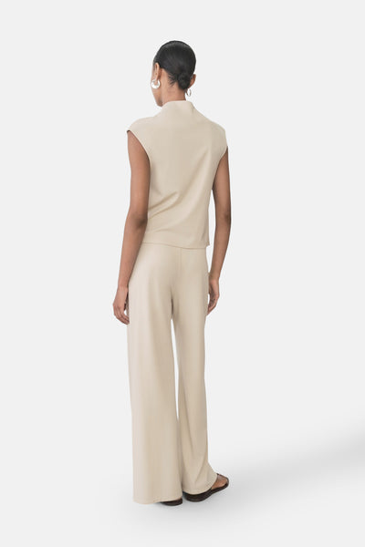 Pantalon beige de MANGO, coupe ample, porté avec un haut assorti et des sandales.