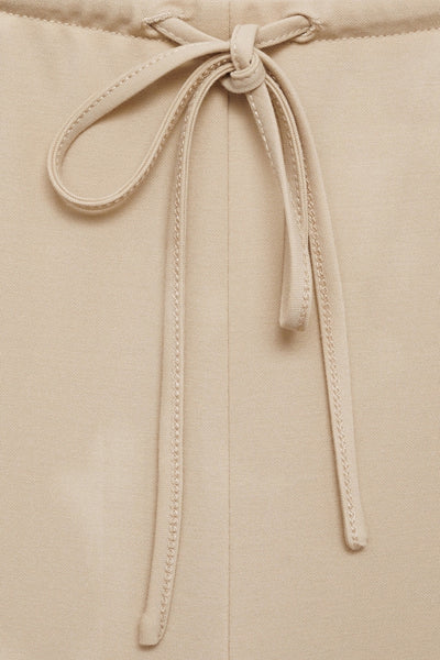 Pantalon beige de MANGO avec cordon de serrage noué à la taille et coutures apparentes.