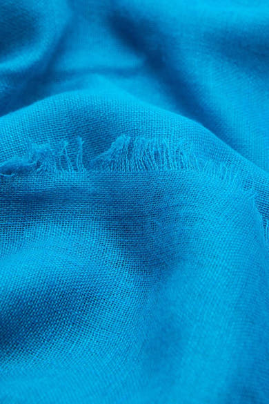 Foulard bleu de MANGO, avec une texture tissée et un bord effiloché.
