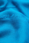 Foulard bleu de MANGO, avec une texture tissée et un bord effiloché.
