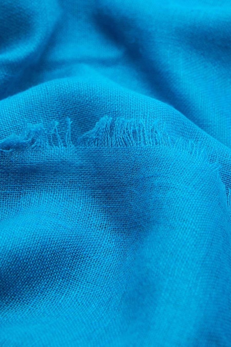 Foulard bleu de MANGO, avec une texture tissée et un bord effiloché.
