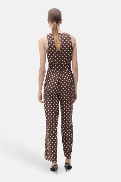 Bruine jumpsuit met stippen van MANGO, met een strikceintuur en zwarte pumps.