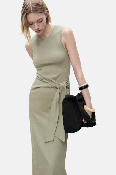 Robe kaki par MANGO, nouée à la taille, portée avec des bracelets contrastés et un sac marron.