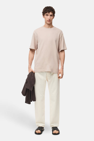 Beige T-shirt met korte mouwen van MANGO, gedragen met een gebroken witte broek en zwarte sandalen.