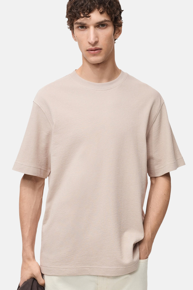 Beige T-shirt met korte mouwen van MANGO, van effen getextureerde stof, gedragen met een lichte broek.
