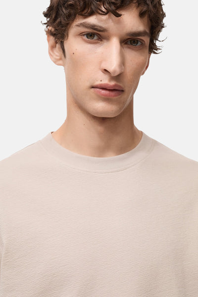 T-shirt beige à manches courtes de MANGO, coupe classique sur un fond uni.