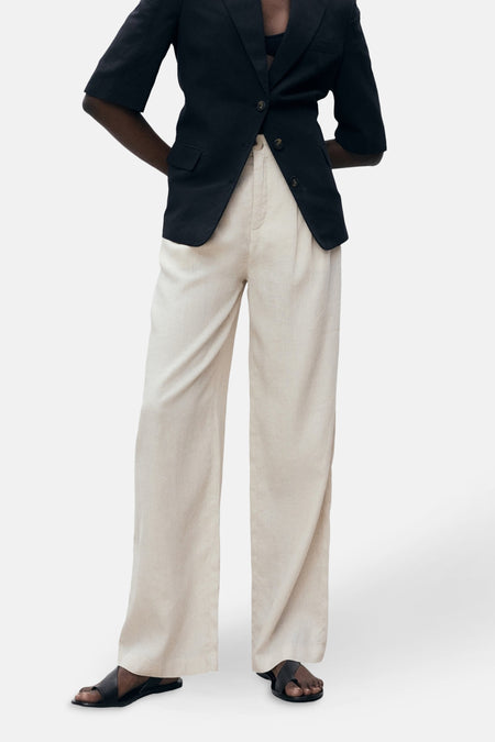 Beige broek van MANGO, losse pasvorm, van linnen, gedragen met een zwart colbert, achterzicht.