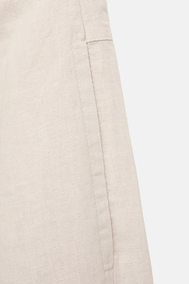 Beige linnen broek van MANGO, detail van de naad en de textuur van de stof.