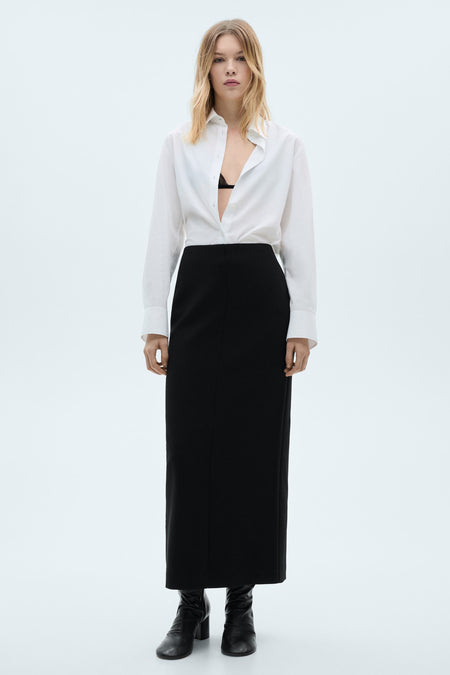 Witte lange mouw chemise van MANGO, gedragen open over een zwarte bh en met een zwarte jurk.