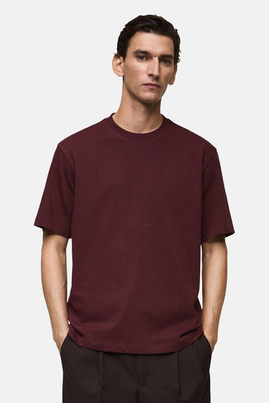 Bordeaux T-shirt met korte mouwen van MANGO, gedragen met een donkere broek, achtergezicht.