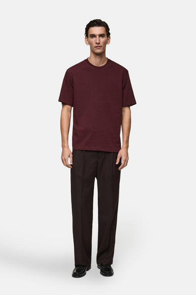 Bordeaux T-shirt met korte mouwen van MANGO, gedragen met een losse bruine broek en zwarte schoenen.