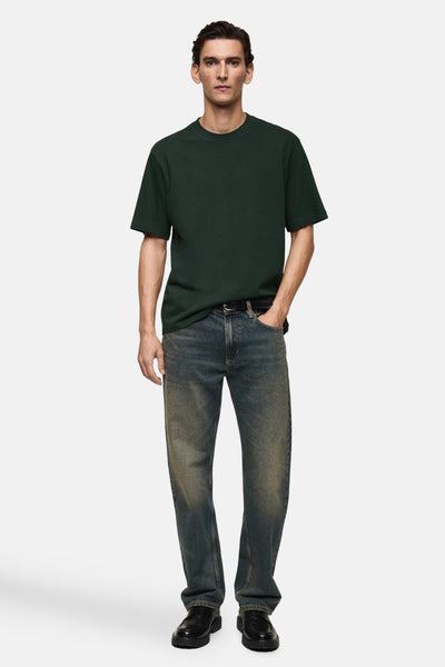 Groen T-shirt met korte mouwen van MANGO, gedragen met een verbleekte spijkerbroek en zwarte schoenen.