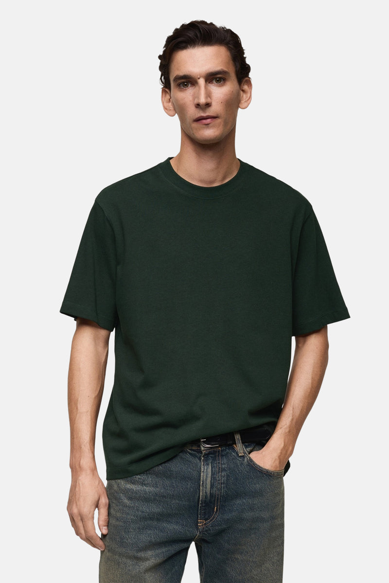 Groen T-shirt met korte mouwen van MANGO, gedragen met een blauwe spijkerbroek en een zwarte riem.