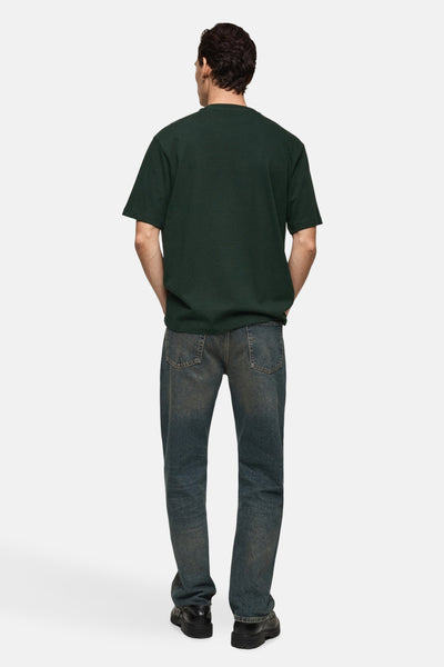 Groen T-shirt met korte mouwen van MANGO, van achteren gezien, gedragen met een verbleekte spijkerbroek en zwarte schoenen.