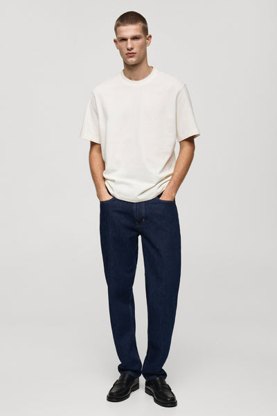 Wit T-shirt met korte mouwen van MANGO, gedragen met een blauwe jeans en zwarte loafers.