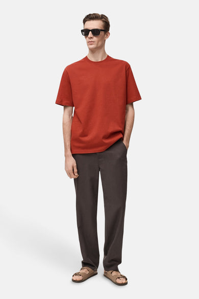 Rood T-shirt met korte mouwen van MANGO, gedragen met een bruine broek en sandalen.