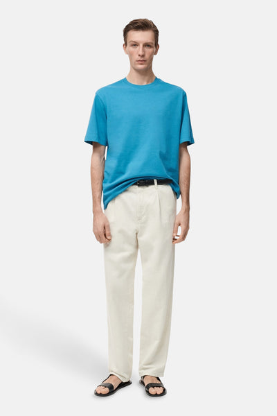 Turquoise T-shirt met korte mouwen van MANGO, gedragen met een lichte broek en zwarte sandalen.