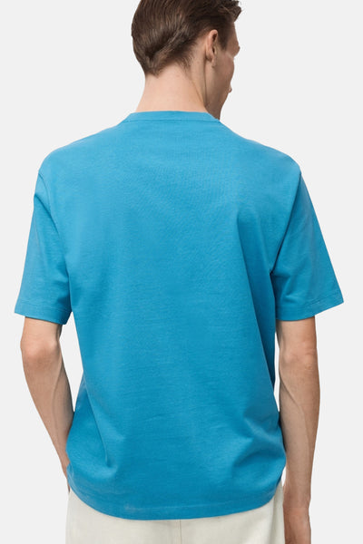 Turquoise T-shirt met korte mouwen van MANGO, van achteren gezien, gedragen met een lichte broek.