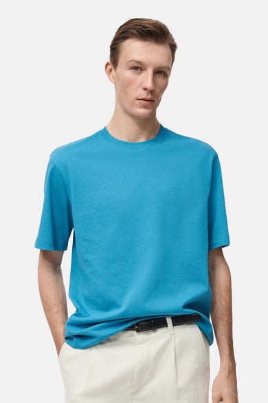 Turquoise T-shirt met korte mouwen van MANGO, gedragen met een beige broek en een zwarte riem.