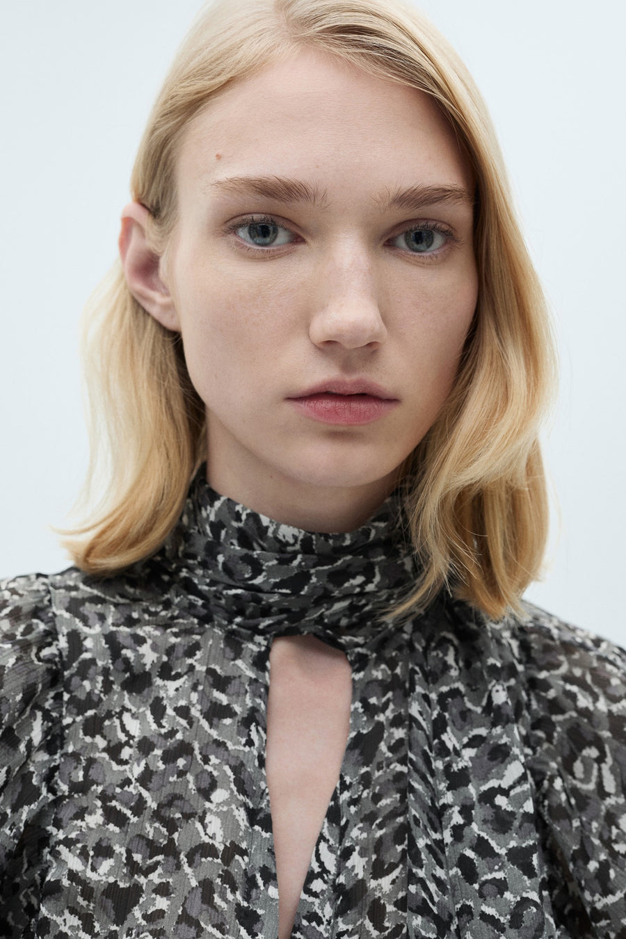 Grijze blouse met lange mouwen van MANGO, met zwart-wit luipaardprint, opstaande kraag en druppelvormige opening.