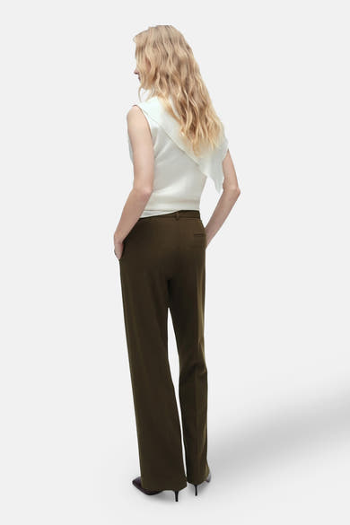 Pantalon brun par MANGO, coupe droite, porté avec un haut blanc, vue de dos.
