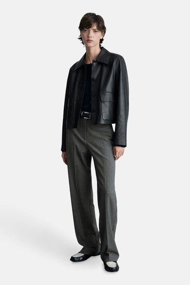 Grijze broek met rechte pijpen van MANGO, gedragen met een zwart leren jasje en tweekleurige platte schoenen.