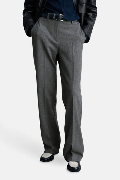 Grijze broek van MANGO met een rechte pasvorm en een zwarte riem, gedragen met zwart-witte schoenen.