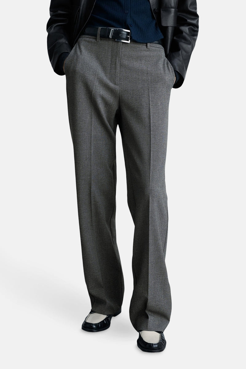 Grijze broek van MANGO met een rechte pasvorm en een zwarte riem, gedragen met zwart-witte schoenen.