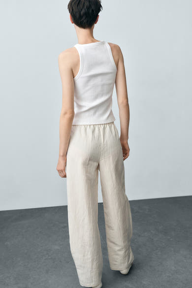 Witte tanktop van MANGO, in geribbelde stof, gedragen met een crèmekleurige broek met elastische taille.