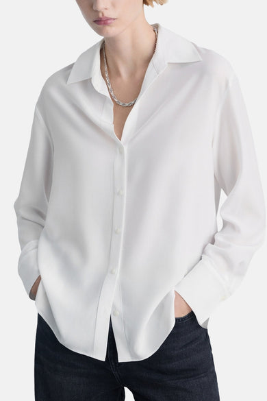 Witte lange mouw chemisier van MANGO, met een subtiel texturen, gedragen met een donkere jeans.