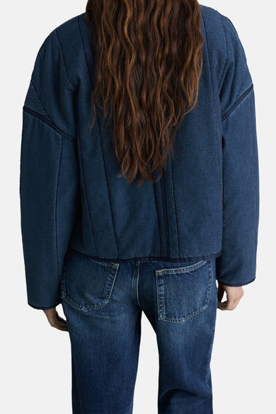 Korte spijkerjas in middieblauw van MANGO, van achteren gezien, met bijpassende spijkerbroek.