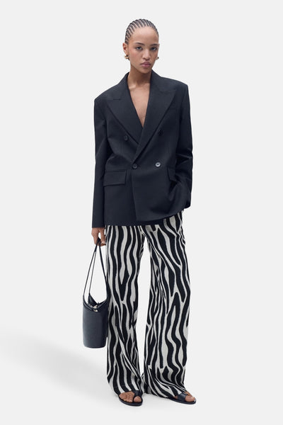 Pantalon à motif zébré noir et blanc, de MANGO, porté avec un blazer noir et des sandales.
