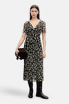 Robe noire à fleurs de MANGO, portée avec des bottes hautes et un sac marron.
