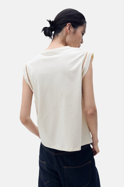 Top sans manches beige de MANGO, avec détail ajouré sur les épaules, porté avec un jean.
