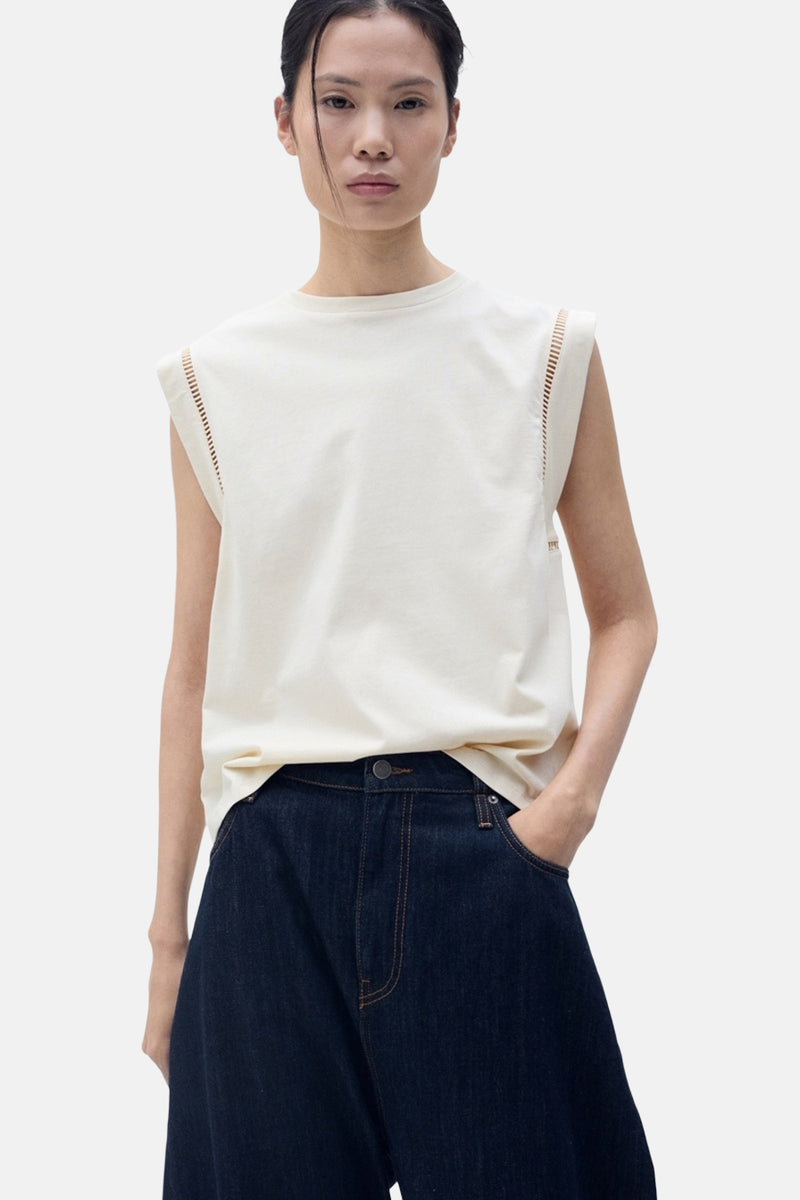 Top sans manches beige de MANGO, avec détails ajourés aux épaules et porté avec un jean large.