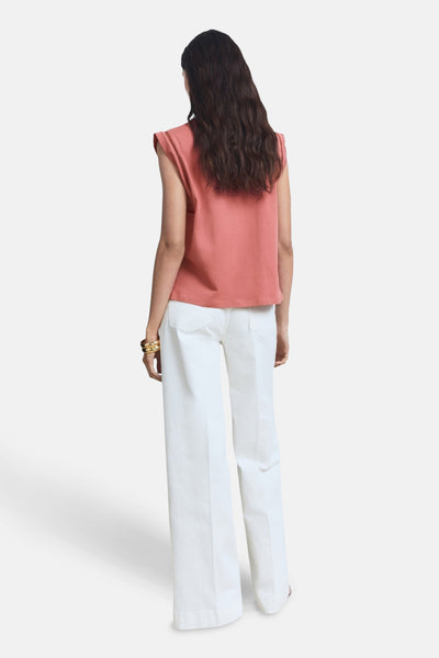 Top rose sans manches de MANGO, avec détail ajouré aux épaules et porté avec un pantalon blanc large.