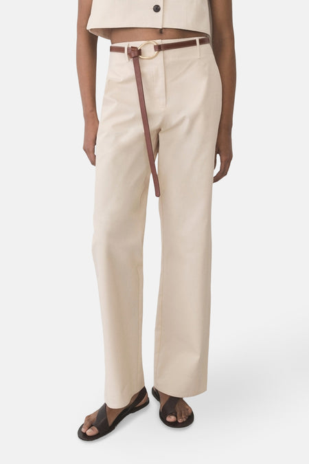 Ecru broek van MANGO, met een dunne bruine strikceintuur, gedragen met donkerbruine leren sandalen.