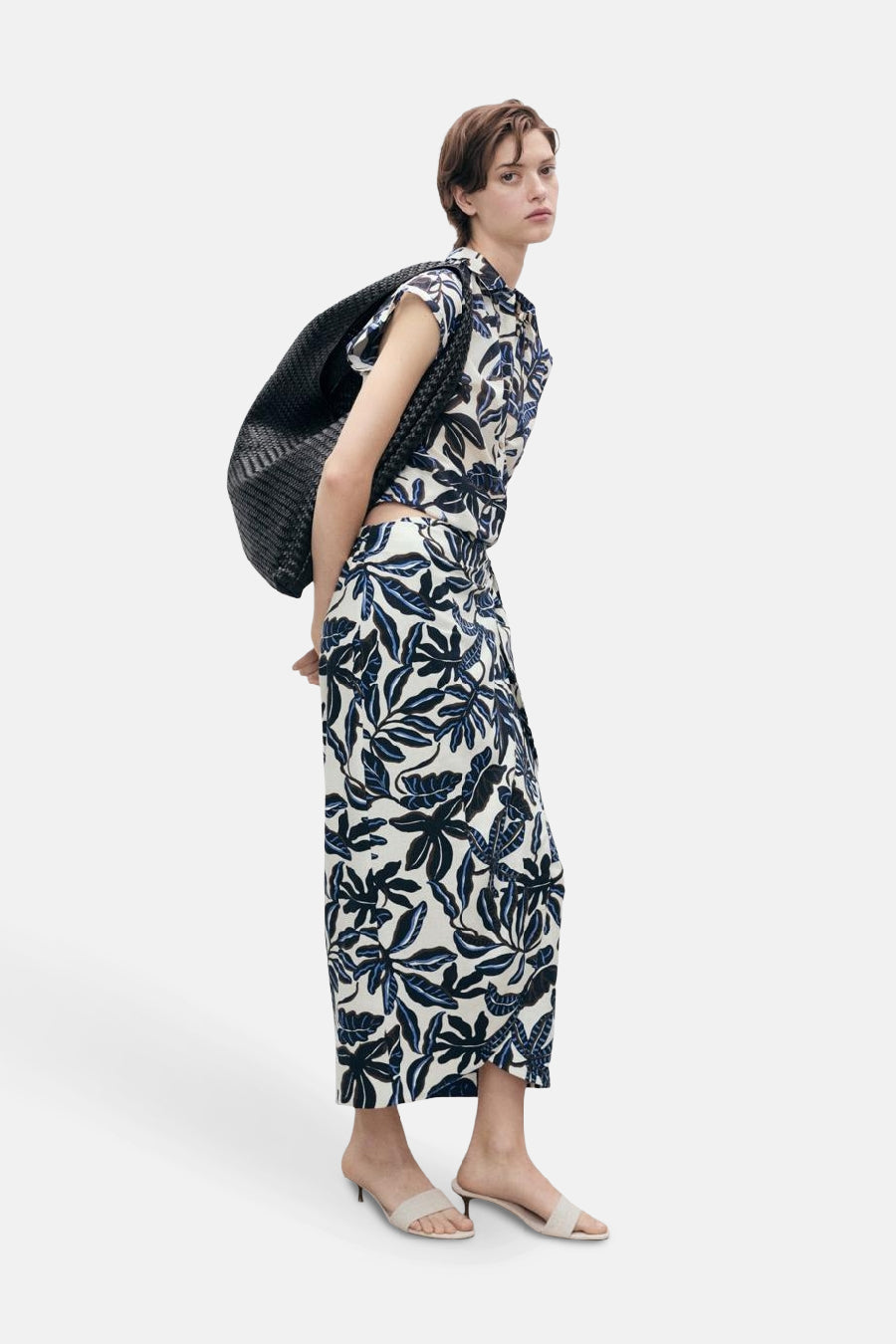 3/4 meerkleurige rok van MANGO, bloemenprint met een zwarte gevlochten tas en beige muiltjes.