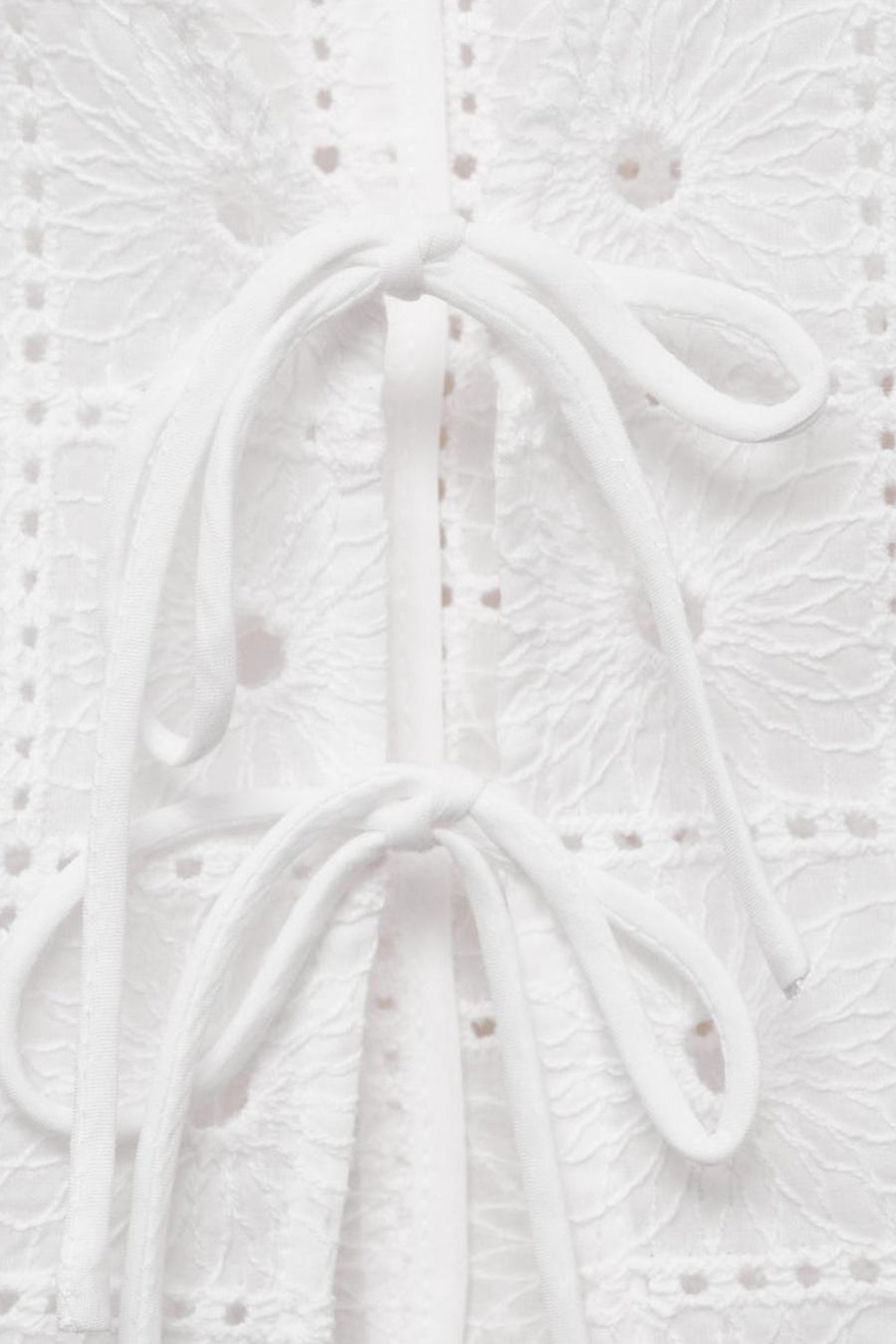 Blouse blanche sans manches de MANGO, avec détails en broderie anglaise et liens à nouer.