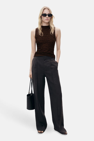 Bruine mouwloze bruine blouse van MANGO, met een getextureerd patroon en gedragen met een wijde broek en een zonnebril.