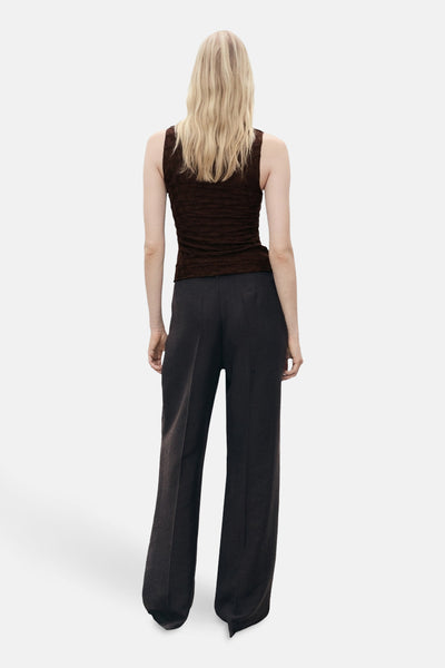 Bruin mouwloos hemd van MANGO, getextureerd, gedragen met een donkere broek met wijde pijpen, van achteren gezien.