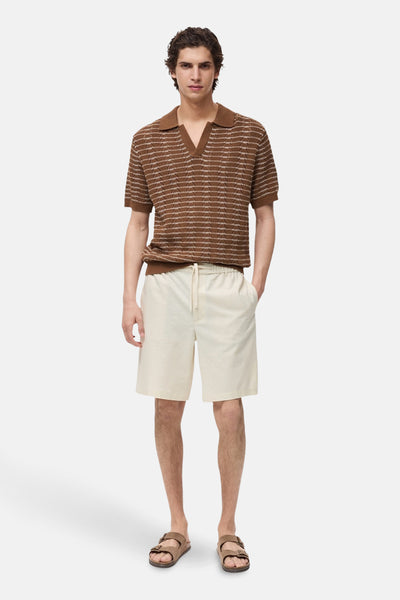 Ecru korte broek van MANGO, met trekkoord en gedragen met een gestreept poloshirt en sandalen.