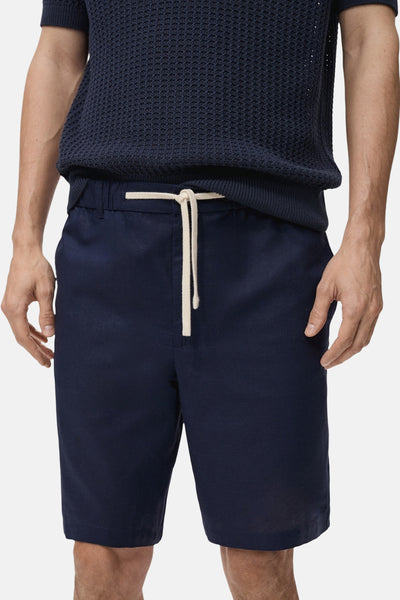 Short bleu de MANGO avec cordon de serrage, porté avec un pull texturé bleu marine.