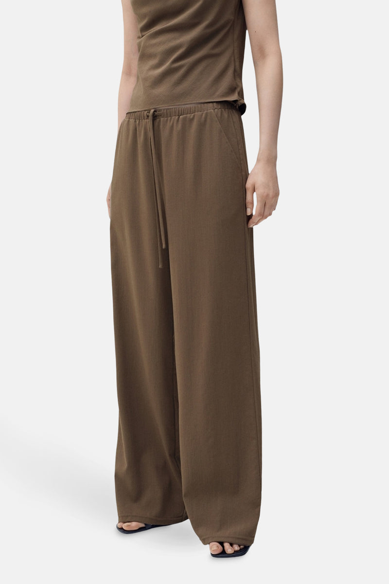 Bruine broek met wijde pijpen van MANGO, met trekkoord in de taille en een zoom die over de sandalen valt.