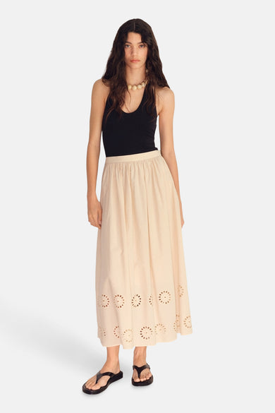 Lange beige rok van MANGO met bloemenborduursels, gedragen met een zwarte tanktop en sandalen.