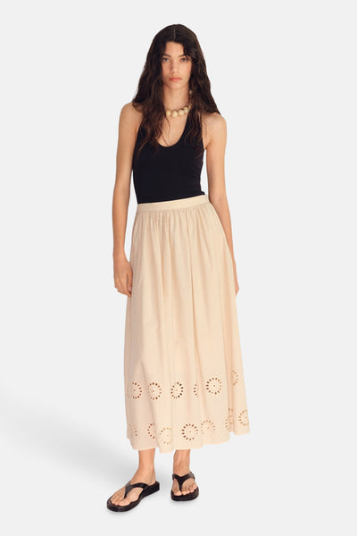Lange beige rok van MANGO met bloemenborduursels, gedragen met een zwarte tanktop en sandalen.