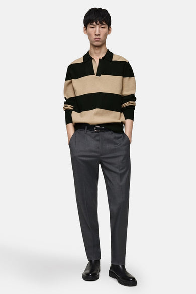 Zwarte trui met beige strepen van MANGO gedragen met een grijze broek en zwarte enkellaarsjes.