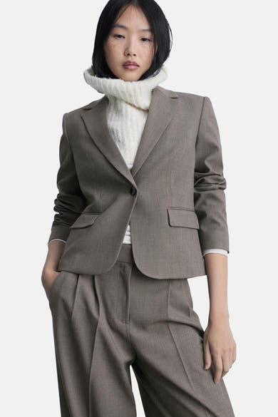 Bruine kostuumbroek van MANGO, gedragen met een bijpassende blazer en een witte coltrui.